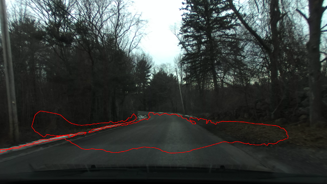 A picture of a two lane cutting across the side of a small, shallow hill such that the hill continues up to the right and down to the left to a wooded area and the road continues to a gentle curve to the left that disappears behind the wooded area to the left at around 80 feet. The red contour line extends well right of the road up the hill almost to a rock wall where the slope of the hill is sufficiently steep that it would not be possible to drive at speed. The red contour also continues well left of the road down a slope that would be similarly impossible to traverse in an on-road vehicle and encapsulates a large area of trees.