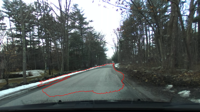 An area highlighted in red beginning about 2 meters in front of the vehicle extending beyond the width of the road in most areas along its length of approximately 30m, particularly along the left where a plowed snowbank maintains level with the road as the ground underneath forms a gully and along the right side where the curbing collapsed and sand has filled the area to be level with the road surface.